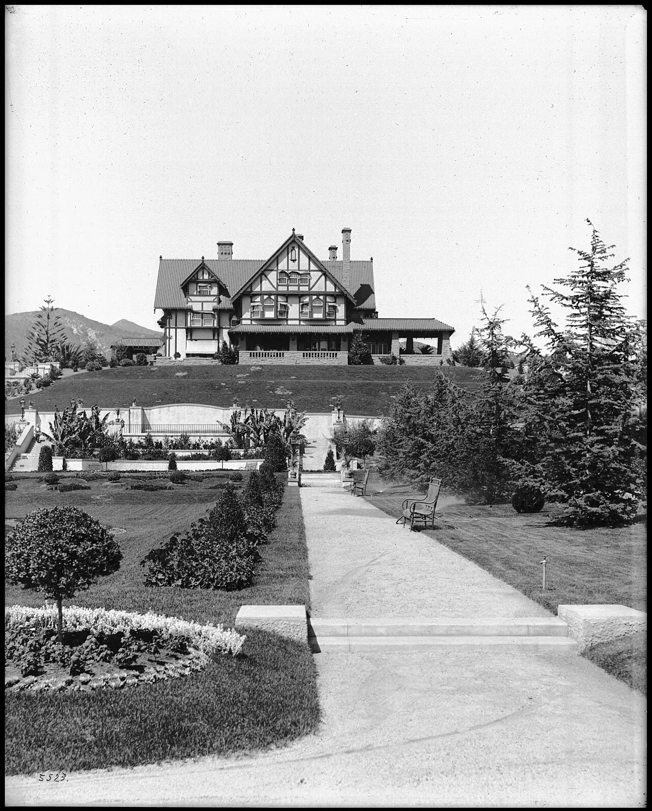 The Arthur Letts residence, a Tudor Revival house on a hill above a formal garden, about 1905